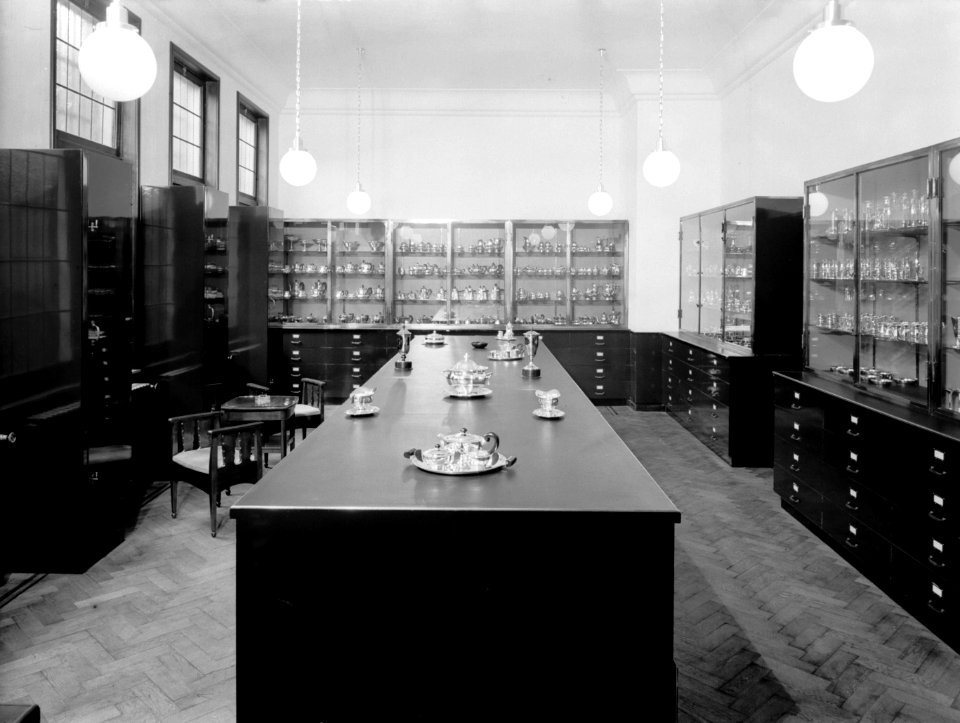 Showroom met diverse zilveren kannen op dienbladen bij de fa Gerritsen & Van Ke, Bestanddeelnr 190-0523