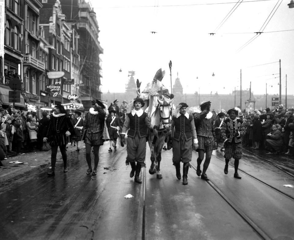 Sinterklaas terwijl hij te paard op het Damrak rijdt, geflankeerd door witte en , Bestanddeelnr 918-4678
