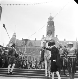 Sinterklaas terwijl hij op zijn schimmel zit voor het stadhuis, begeleid door Zw, Bestanddeelnr 918-4739