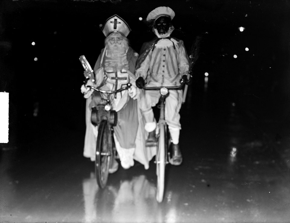Sint Nicolaas en Zwarte Piet per bromfiets en fiets op weg naar het schaaktoerno, Bestanddeelnr 904-3094