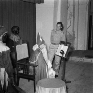 Sint-Nicolaas op het podium met zwarte pieten. Hij leest uit het grote boek, b, Bestanddeelnr 12605