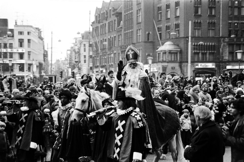 Sinterklaas, wuivend naar het publiek, passeert met zijn gevolg een grote menigt, Bestanddeelnr 930-5457