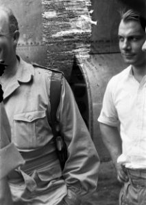 Staande voor een vliegtuig spreekt een bebrilde man in uniform met pistoolholste, Bestanddeelnr 5924