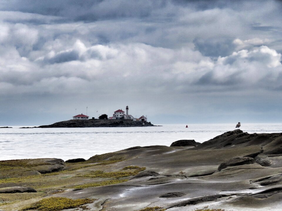 Cloudy sky rocks lighthouse photo