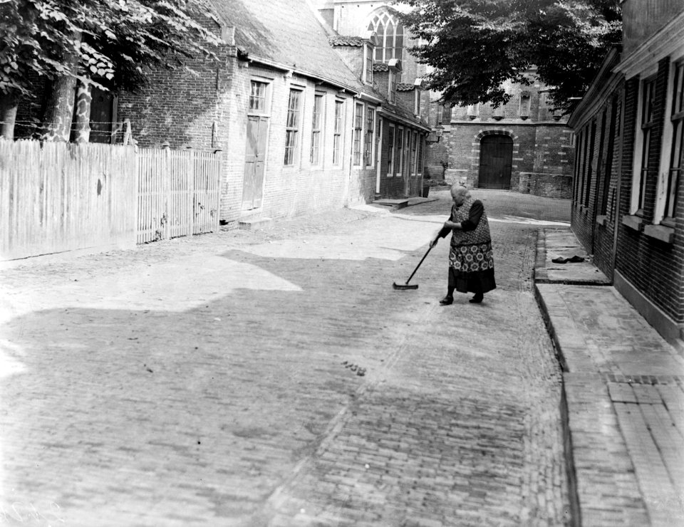 Straat in Edam met vegende vrouw, op de achtergrond een kerk, Bestanddeelnr 252-0724