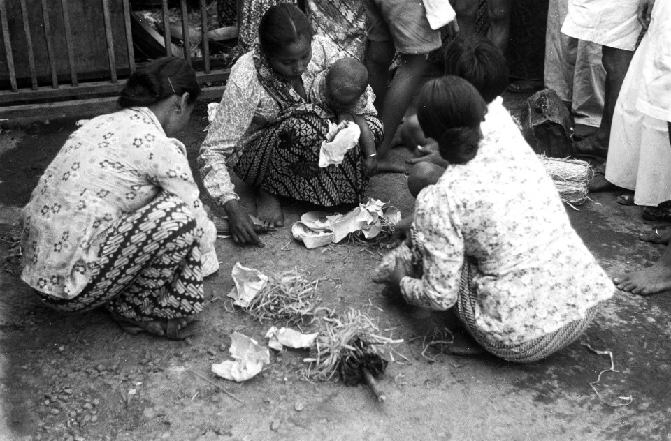 Straatbeelden. Vrouwen met babies, hurkend op straat, tussen hen in luwen raffia, Bestanddeelnr 3442