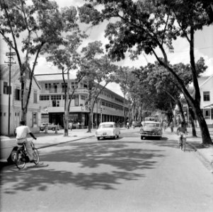 Straat met winkelpand in Paramaribo met onder andere een fotowinkel en een rijwi, Bestanddeelnr 252-4946