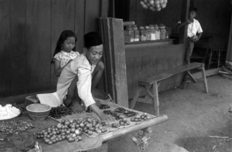 Straatbeelden. Straatverkoper. Voor hem pepers en tomaten. Naast hem o.a. een vi, Bestanddeelnr 3437