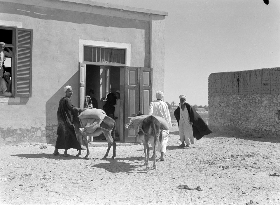 Straatbeeld in een dorp. Mannen met hun ezels bij een overheidsgebouw, Bestanddeelnr 191-0094