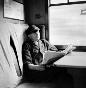 Stoker leest tijdens zijn aflossing een krant in een treincoupé, Bestanddeelnr 254-3530