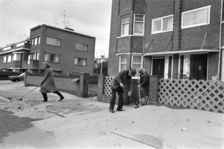 Storm aan de kust, bewoners vegen het van het strand gewaaide zand van hun stoep, Bestanddeelnr 929-4397