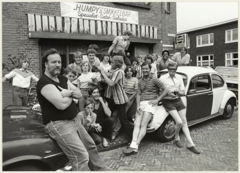 Straathoekwerker Fer Versteeg met jongeren van de Indischebuurt-Noord voor het alternatieve buurthuis 'Humpy's' snackbar in de Kedoestraat. NL-HlmNHA 54013197
