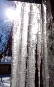 Sunlight through icicles hanging from porch roof photo