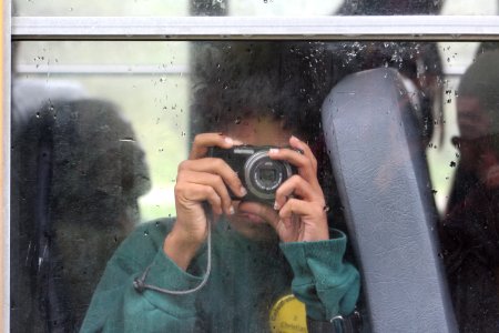 Student on school bus holding camera