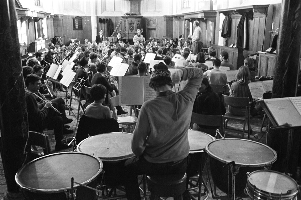 Studenten Orkest oefent in kerk van Bergen. De paukenist met ijsmuts maakt handi, Bestanddeelnr 920-9735
