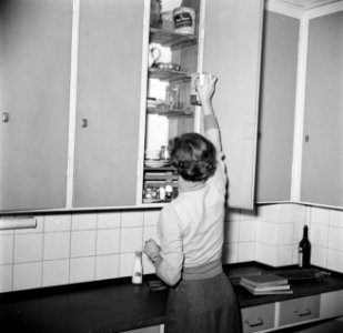 Studente bij een kast in de keuken van het studentenhuis, Bestanddeelnr 252-8928