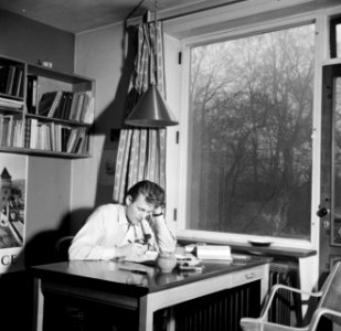 Student zittend aan tafel in een kamer in het studentenhuis, Bestanddeelnr 252-8920