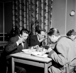 Studenten aan tafel in de eetzaal van het studentenhuis, Bestanddeelnr 252-8949