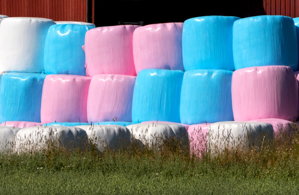 Stack of pink white and blue silage bales