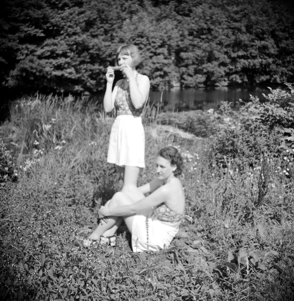 Stiefdochters Renée en Hans op een grasveld Renée speelt mondharmonica, Bestanddeelnr 191-0584