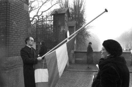 Stil protest van een man met de vlag halfstok bij de ingang van de begraafplaats, Bestanddeelnr 934-3962