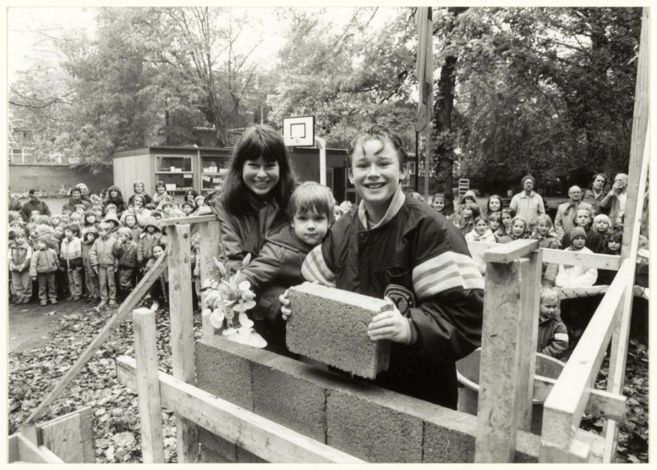 Steenlegging voor de nieuwbouw van de Haarlemmerhoutschool aan het Florapark door de oudste en jongste leerling van de school. Toezicht wordt gehouden door de Wethouder van Onderwijs, mevrou, NL-HlmNHA 54015523