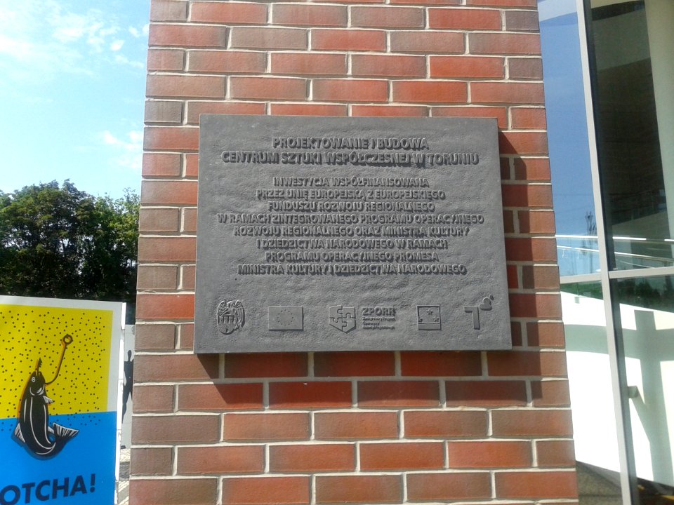 Tablica informacyjna na jednym z zewnętrznych filarów Centrum Sztuki Współczesnej Znaki Czasu