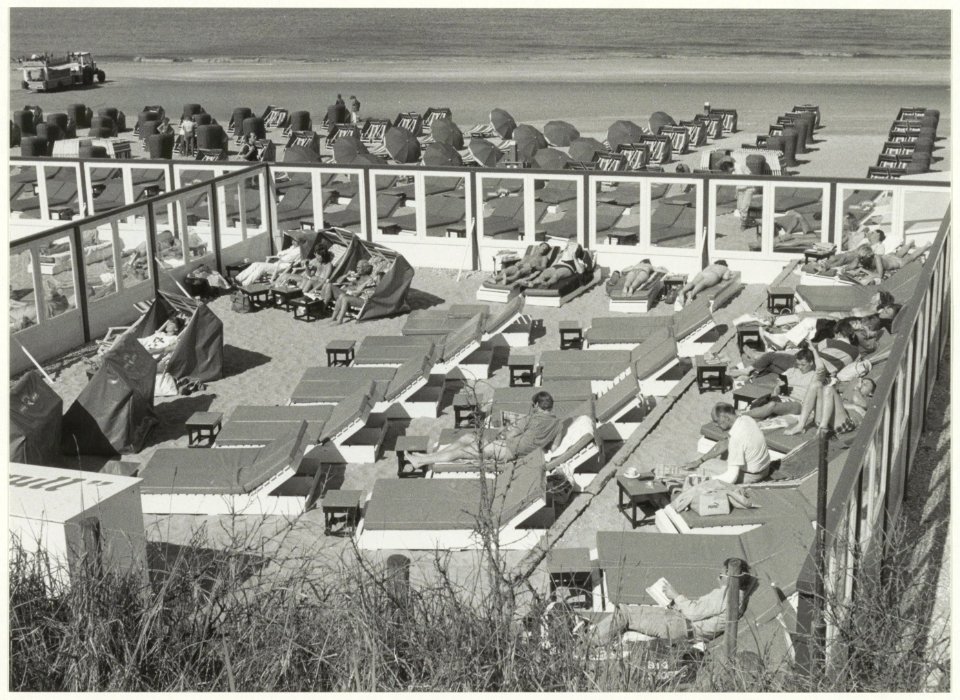 Terras met strandstoelen en -bedden. NL-HlmNHA 54005263