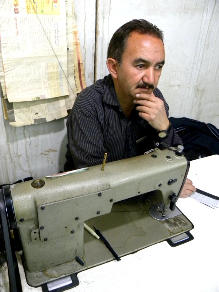 Tailor men Behind the Sewing Machine Fingers on his chin