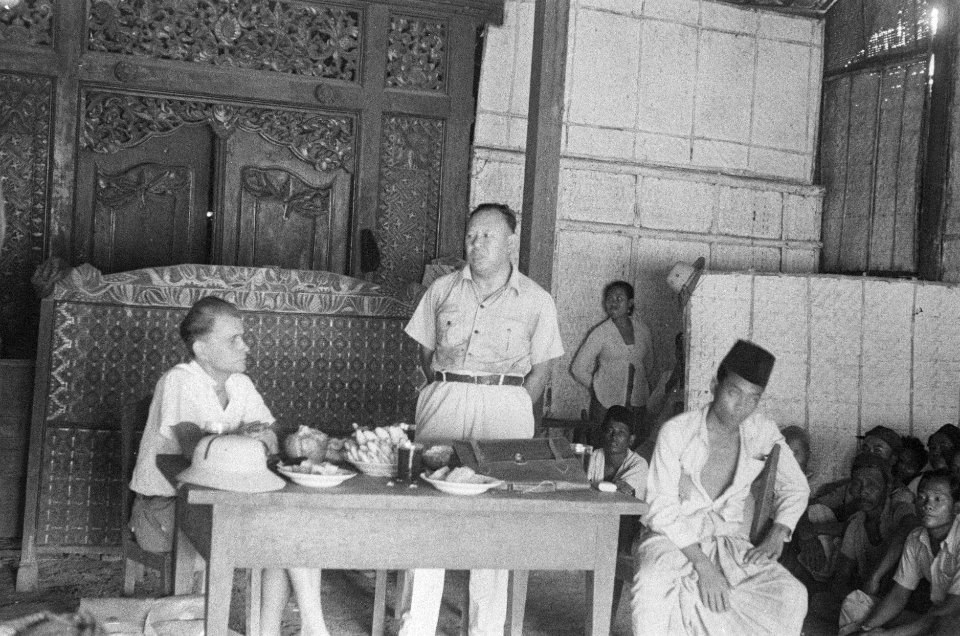 Toespraak van Indonesische man in een grote zaal met houtsnijwerk Links een Eur, Bestanddeelnr 50-2-2