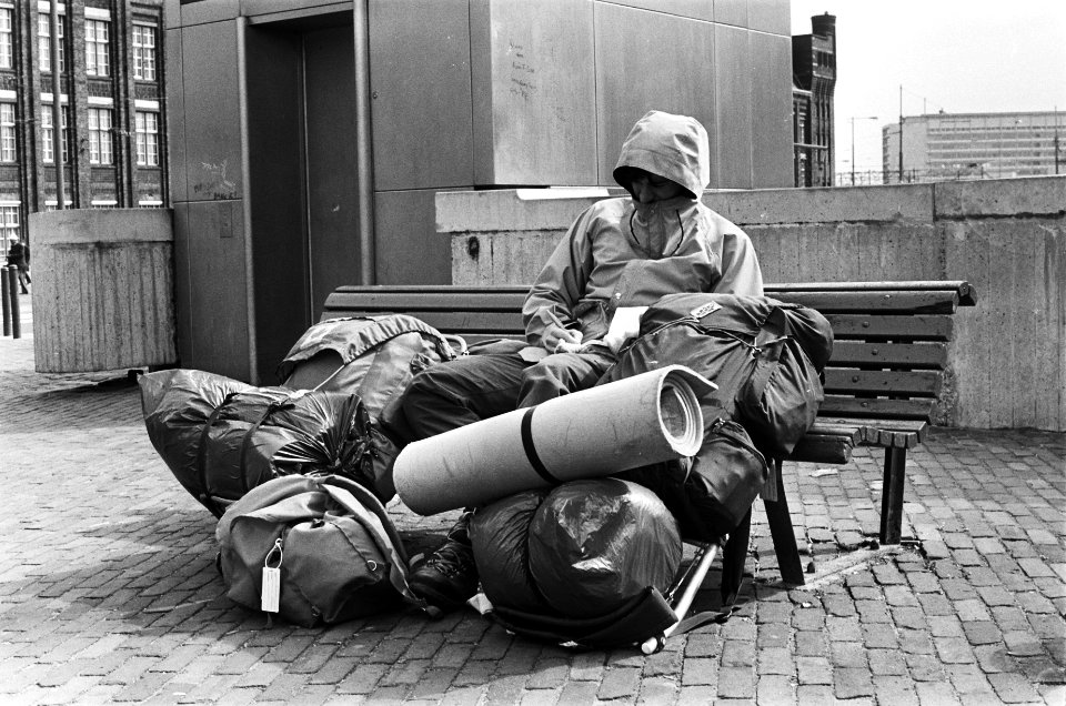 Toeristenstroom voor Pasen in Amsterdam. Toerist in regenpak met veel bagage op , Bestanddeelnr 932-0978