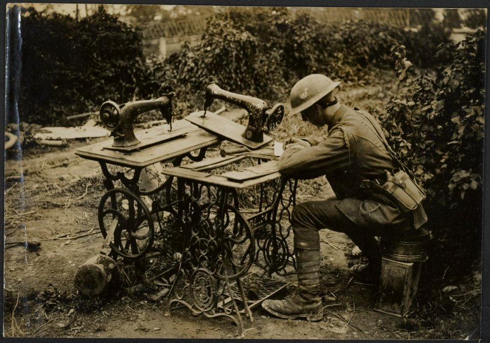 Tommy uses as a writing desk sewing machines rescued from the ruins, Bestanddeelnr 158-2735