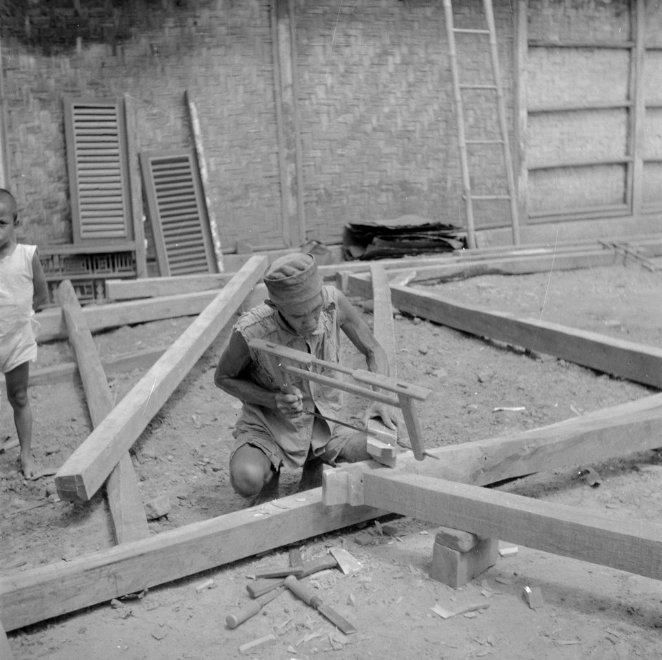 Timmerman in de kampong bezig met de bouw van een huis, Bestanddeelnr 255-6717