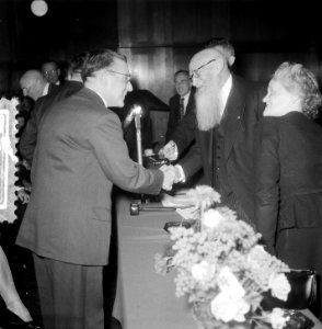 Tijdens een receptie schudt Jan van Zutphen de hand van een aanwezige. zijn ec…, Bestanddeelnr 906-0206