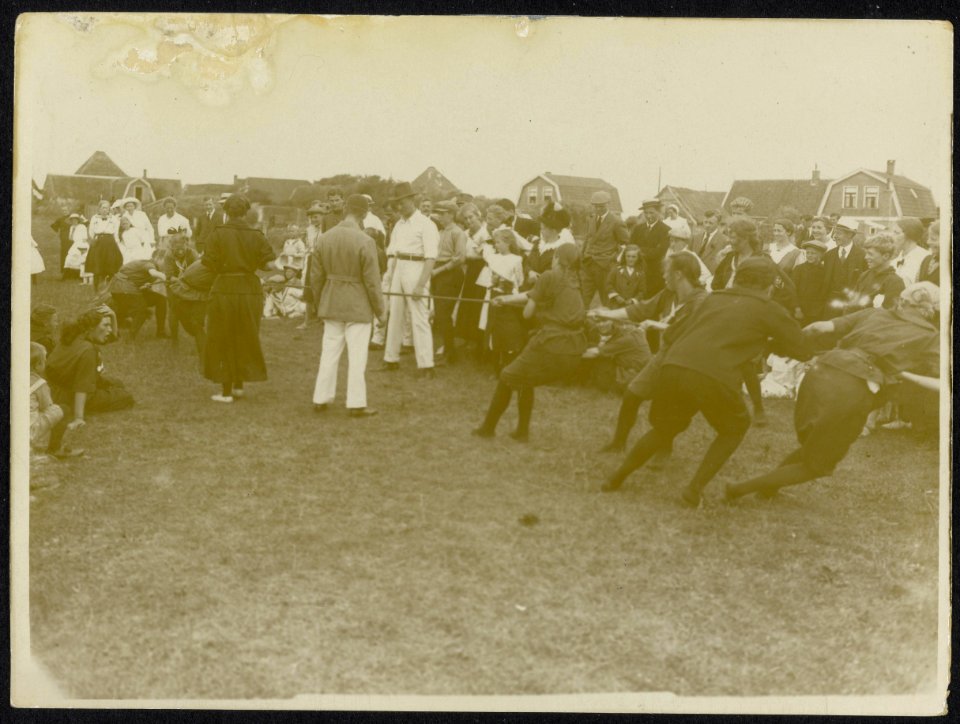 Touwtrekwedstrijd tussen twee damesteams op een open veld in een dorp met een en, Bestanddeelnr 158-1251
