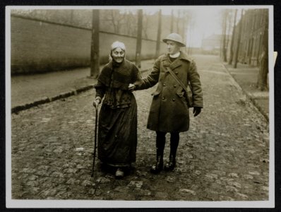 The German offensive. A British Padre conducting a frail old lady down the stree, Bestanddeelnr 158-1209