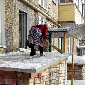The old lady removes snow from the roof (Koryazhma)