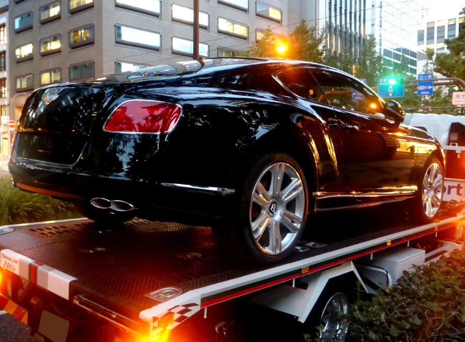 The rearview of Bentley CONTINENTAL GT on the delivery vehicle of Cornes & Co., Ltd. at night