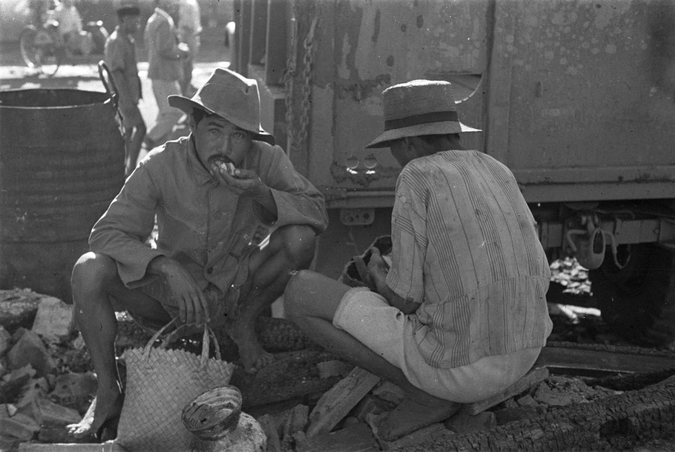 Twee Indonesische mannen met manden eten iets temidden van puin, Bestanddeelnr 125-6-5
