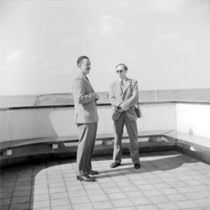 Twee heren staan op een terras aan de waterkant, Bestanddeelnr 255-7653