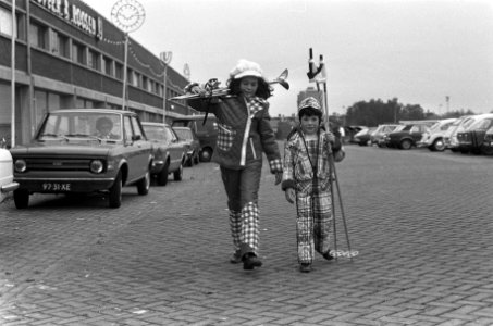 Twee kinderen, voorzien van wintersport attributen, showen de kleding, Bestanddeelnr 926-8083