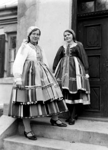 Twee jonge vrouwen in klederdracht op de trap voor hun woning in Lowicz, Bestanddeelnr 252-1288