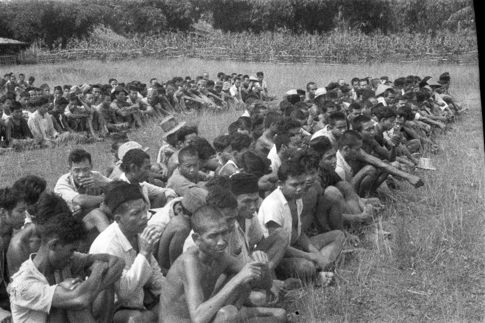 Twee grote groepen Indonesische mannen zitten in een grasveld, Bestanddeelnr 477-5-6