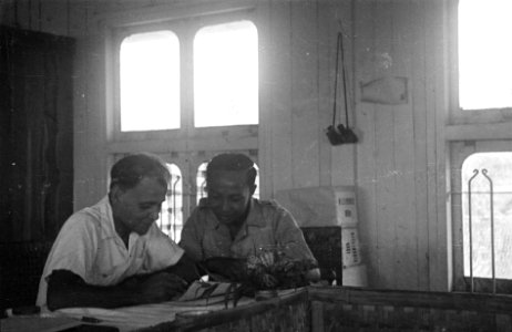 Twee mannen, waarvan een in unform buigen zich over papieren, zittend in een lok, Bestanddeelnr 6522 photo