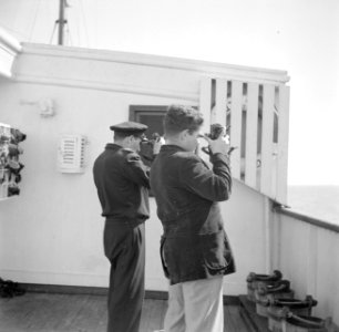Twee mannen aan boord van een schip kijkend door een sextant, Bestanddeelnr 255-0008