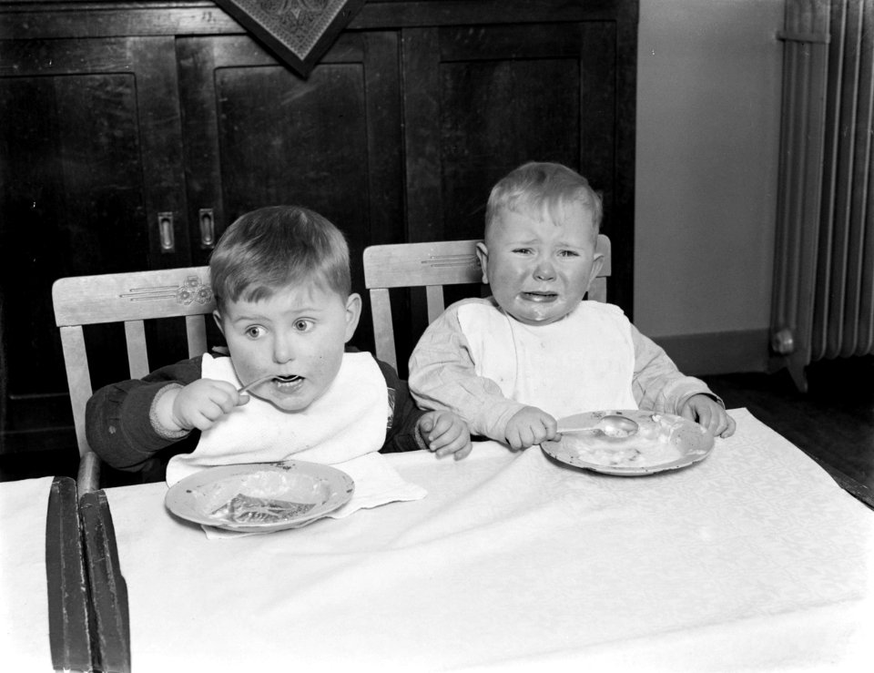Twee jongens in het tehuis Annette eten pap met een lepel. Eentje moet huilen, Bestanddeelnr 252-0379