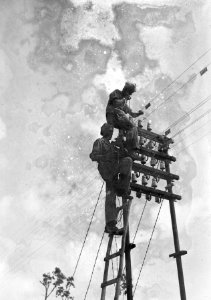 Twee militairen staan op een telefoonpaal, Bestanddeelnr 15943