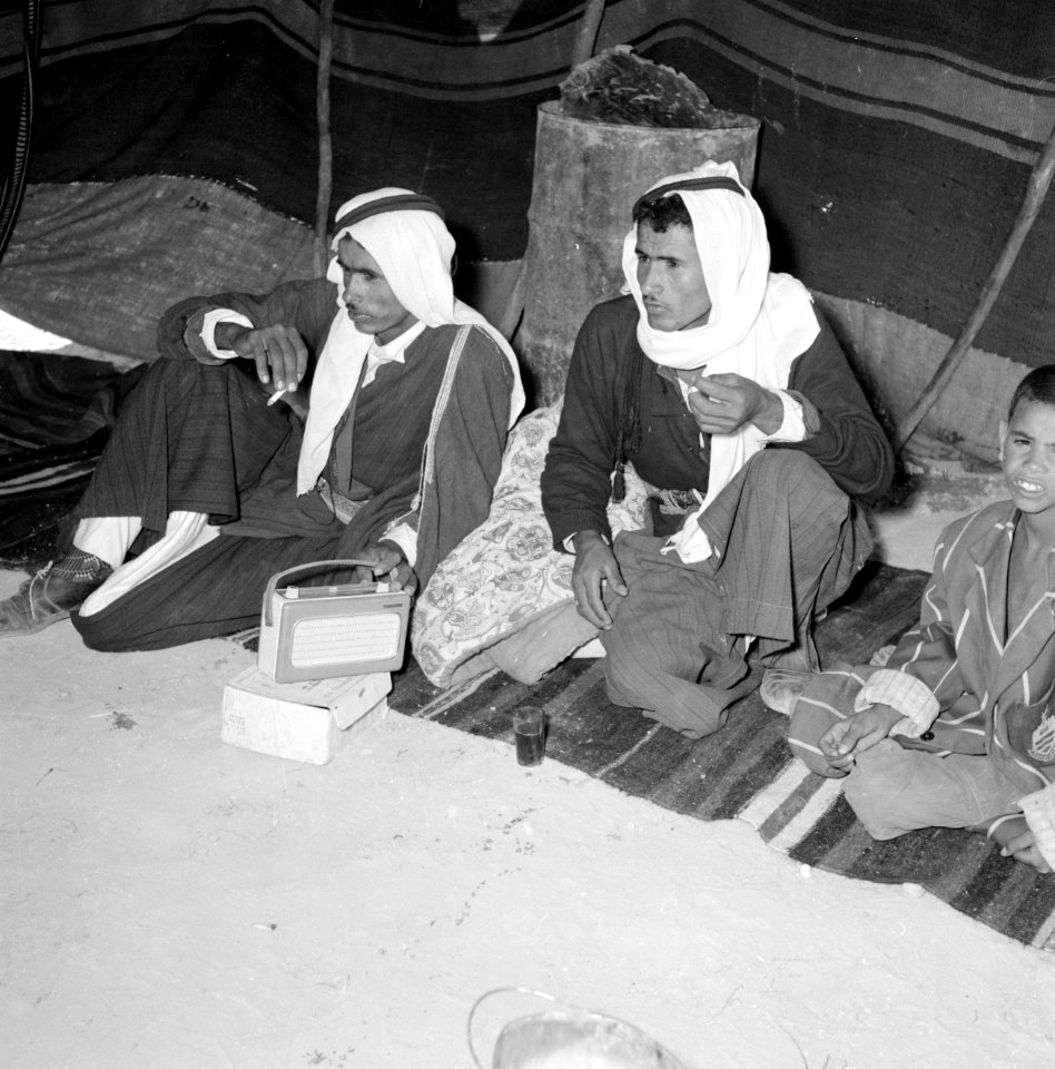 Twee volwassen bedoeienen in een tent met een jongen luisterend naar een transis, Bestanddeelnr 255-3485
