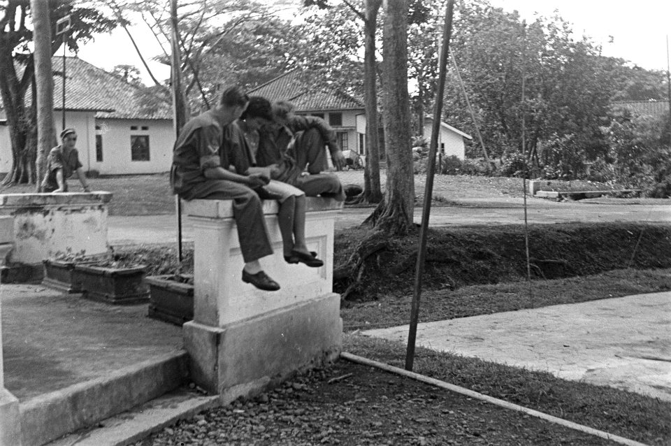 Twee militairen zitten met een meisje op een balustrade op het terrein van ontsp, Bestanddeelnr 6286