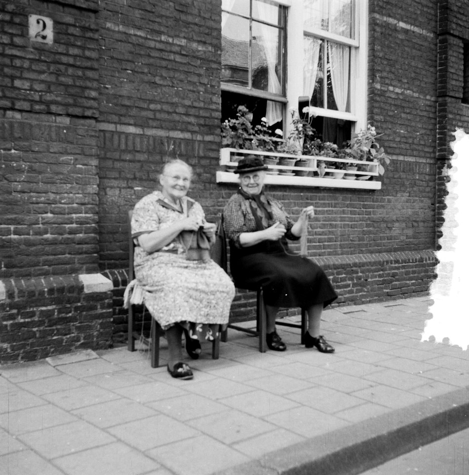 Twee oudere dames buiten voor een huis in de schaduw met breiwerk, Bestanddeelnr 907-2899